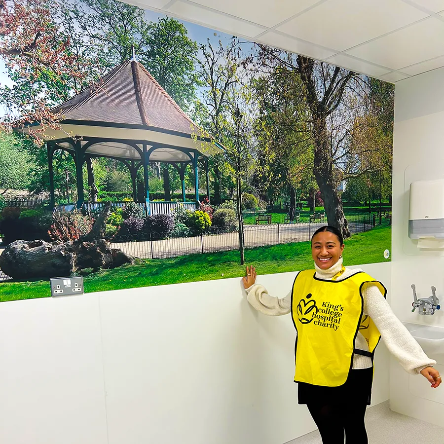 A charity representative standing in front of local artwork scenes displayed in ED majors