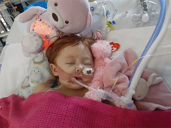 Emily in hospital bed with breathing apparatus
