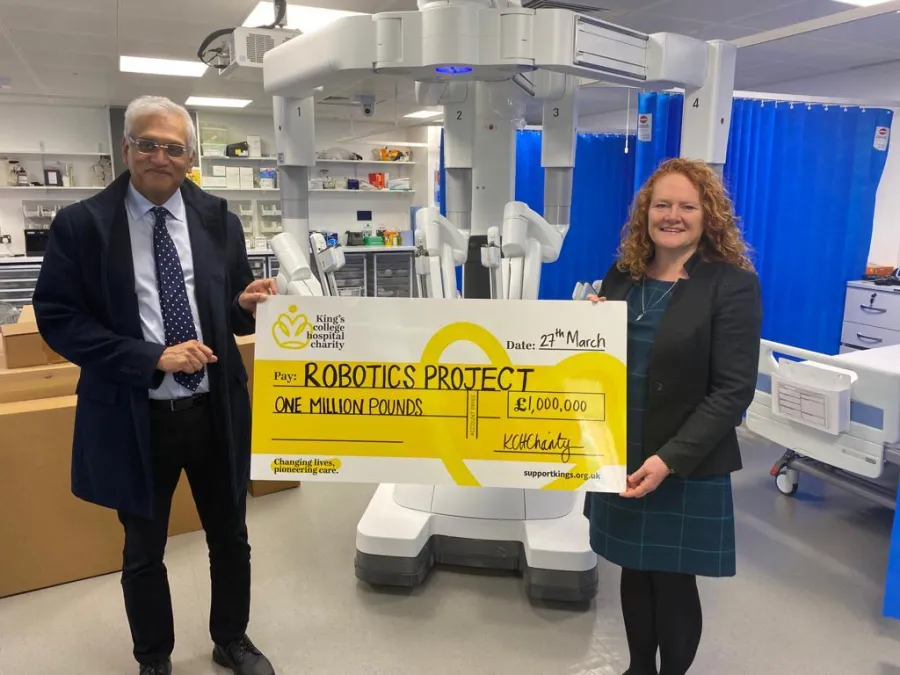 Picture of charity chief executive Gail Scott Spicer and consultant surgeon Prof Ameet Patel holding a giant cheque for 1 million pounds, with the surgical robot in the backgroundd