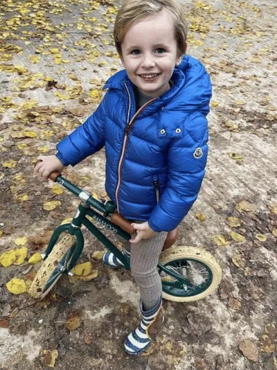 A picture of Jake standing on a bike and smiling at the camera