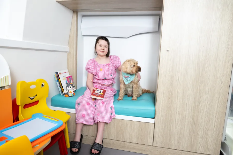 A girl sitting with a dog in a small cove in the playroom