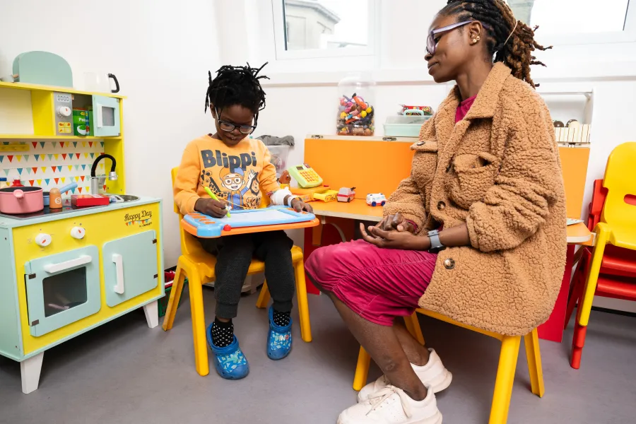 A young boy with his mum drawing on an etch sketch 