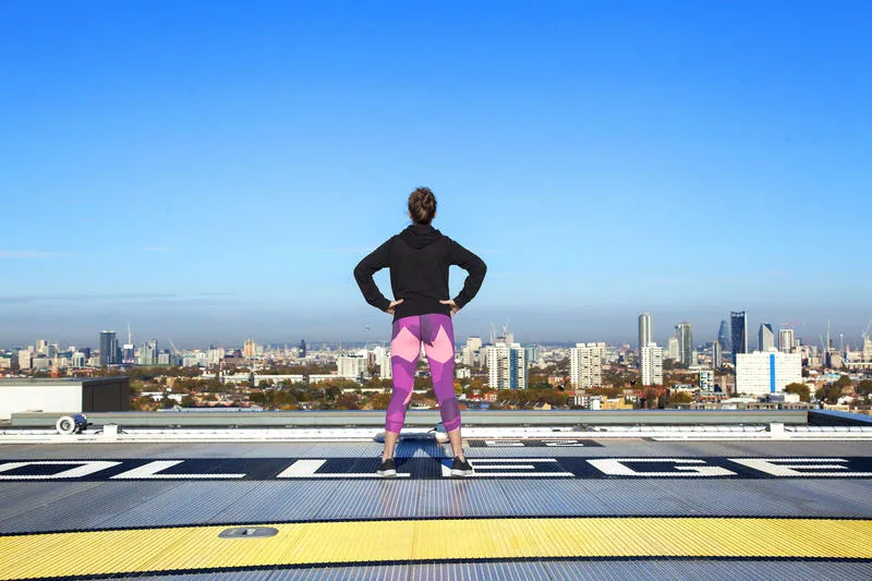 Picture of Kiko standing hand on hips on King's helipad, facing away from camera, towards cityscape