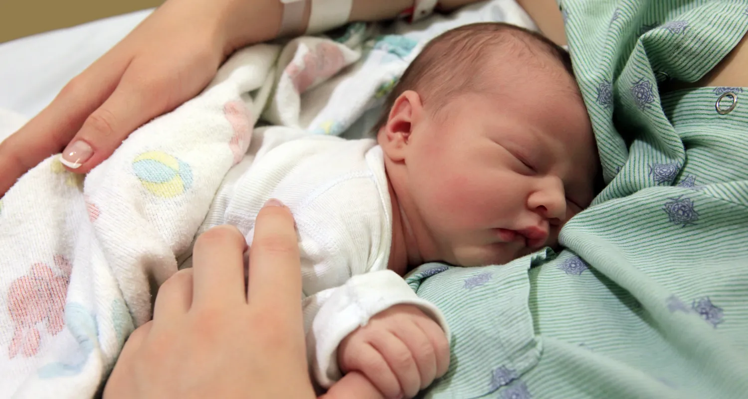 A picture of a new born baby holding her mother's thumb
