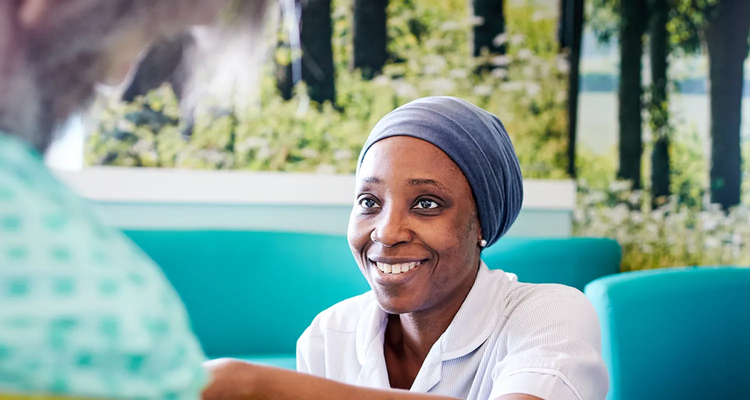 Nurse in a clinical setting smiling at a patient