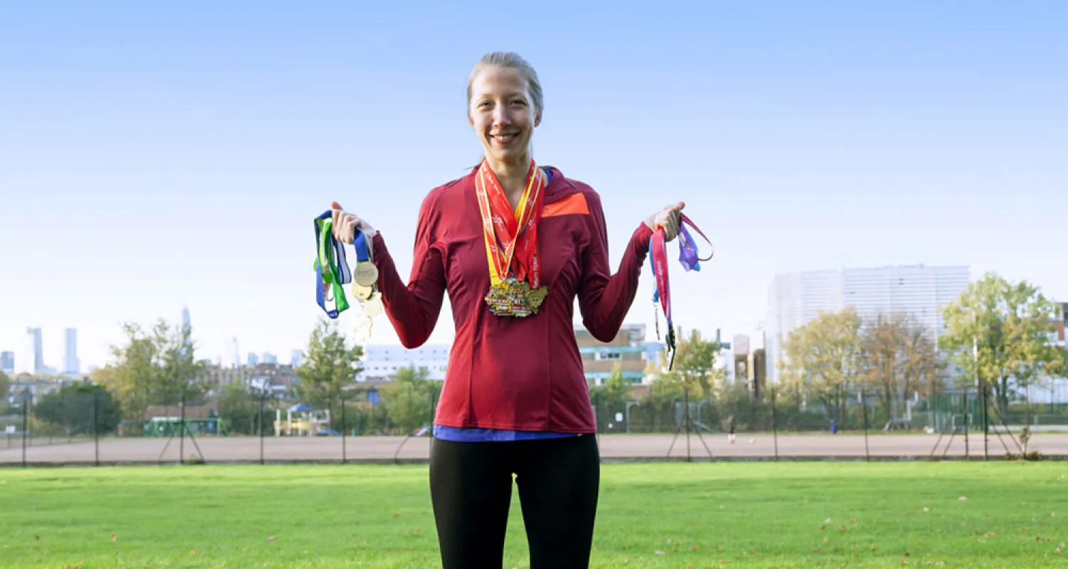 Photo of Helen standing in a tracksuit holding medals