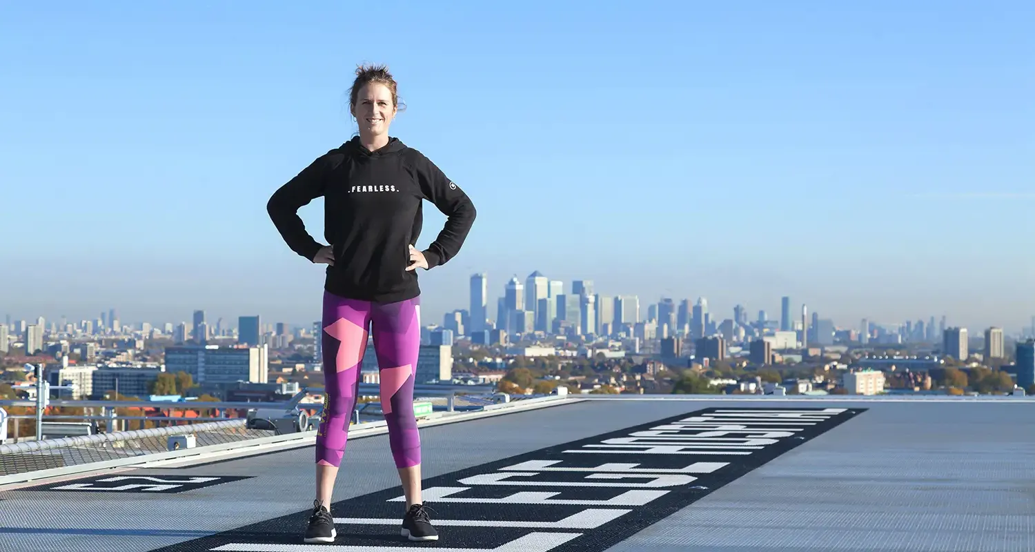 Picture of Kiko standing hand on hips on the King's helipad with blue skies and cityscape behind her