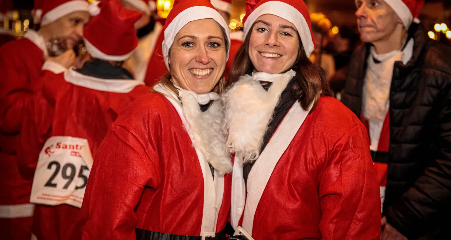 two ladies in Santa suits smiling 