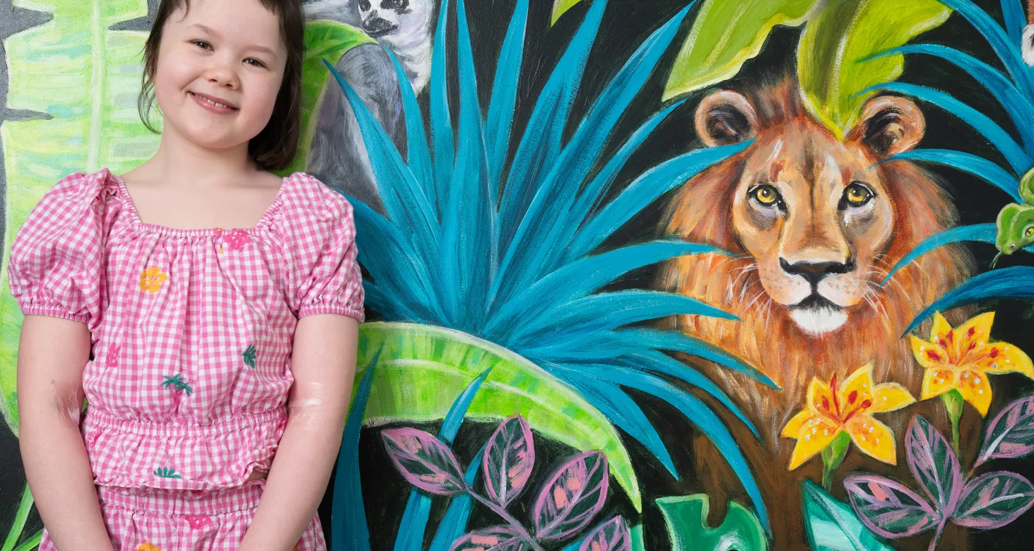 A child called Scarlet in front of a jungle mural