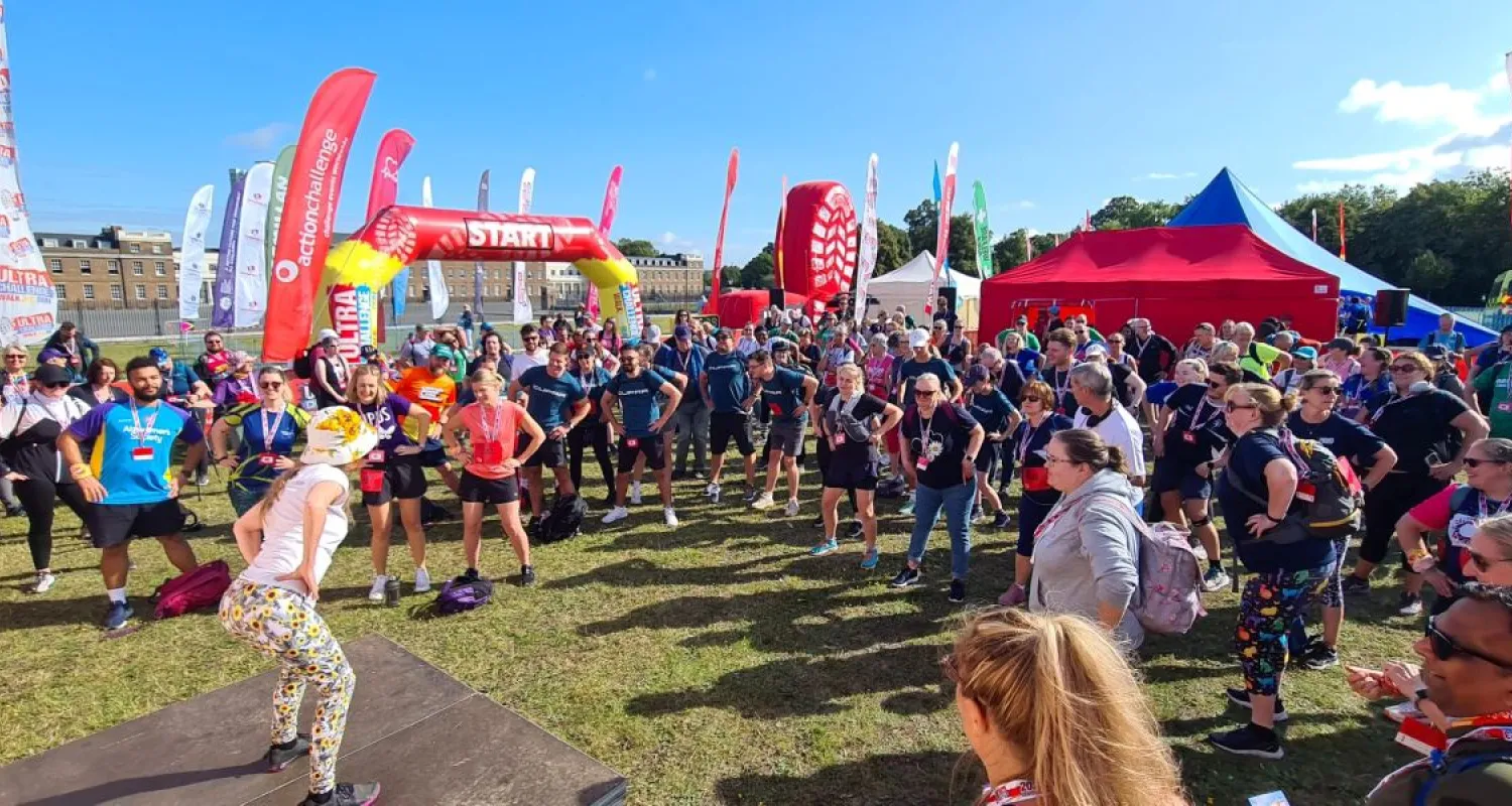 A large group of people stand in a semi circle warming up for a physical event