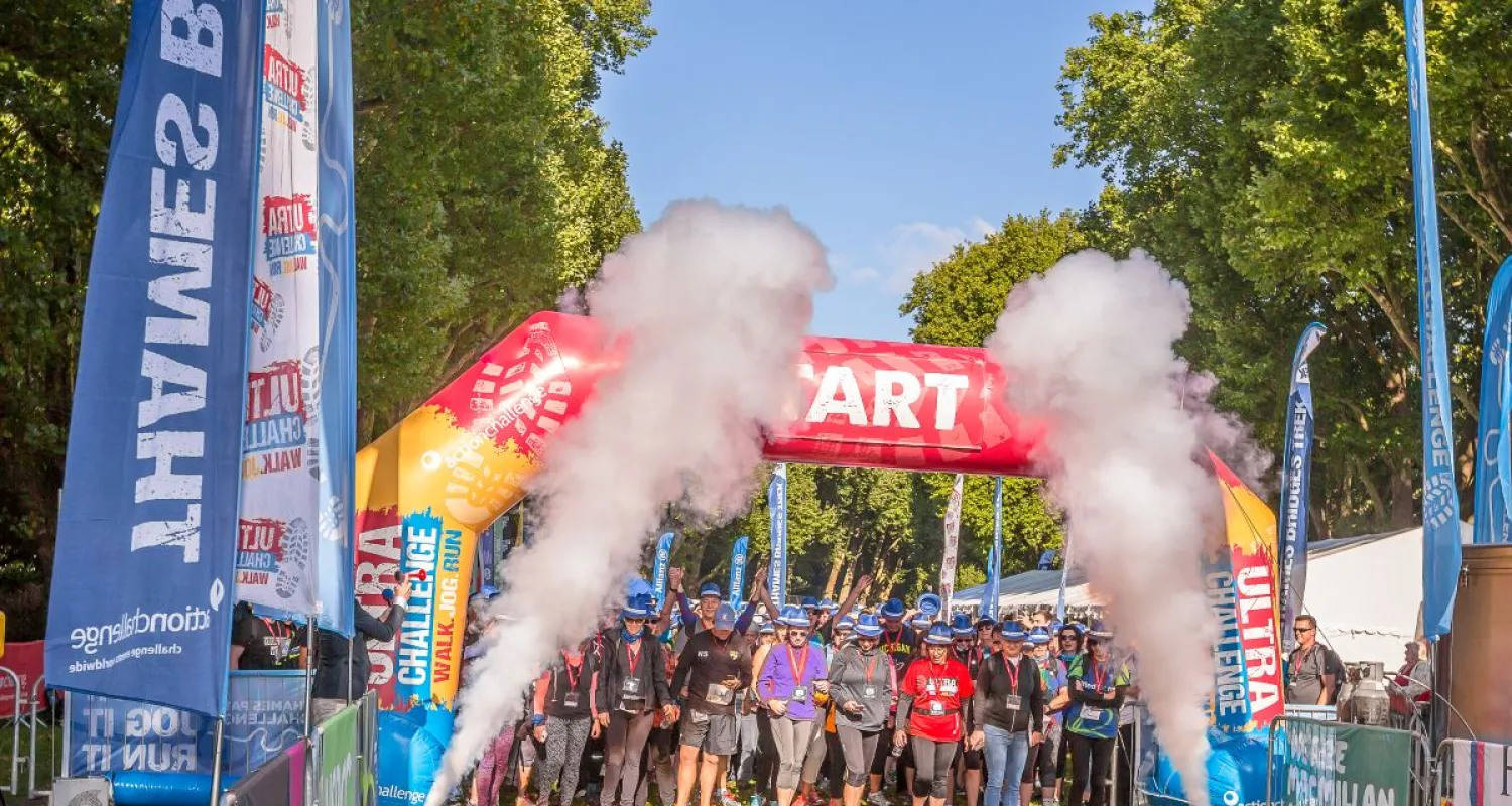 Event participants walk under an event gantry with smoke cannons