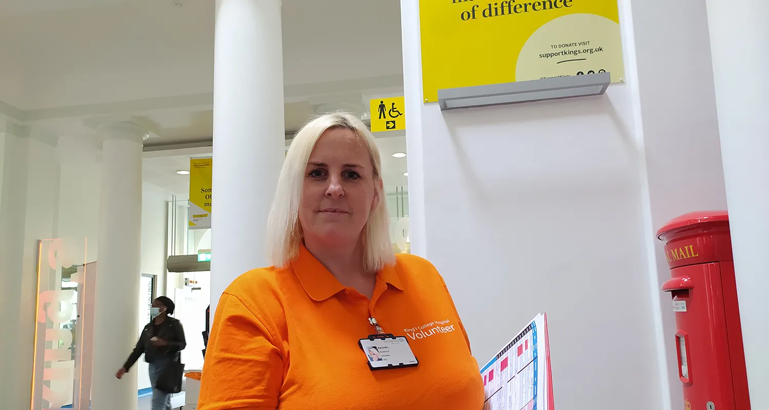 Photo of Rachel wearing orange King's Volunteers uniform in entrance to hospital