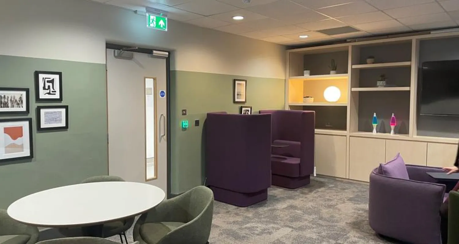 Photo of a room with grey carpet, comfy purple chairs and soft lighting