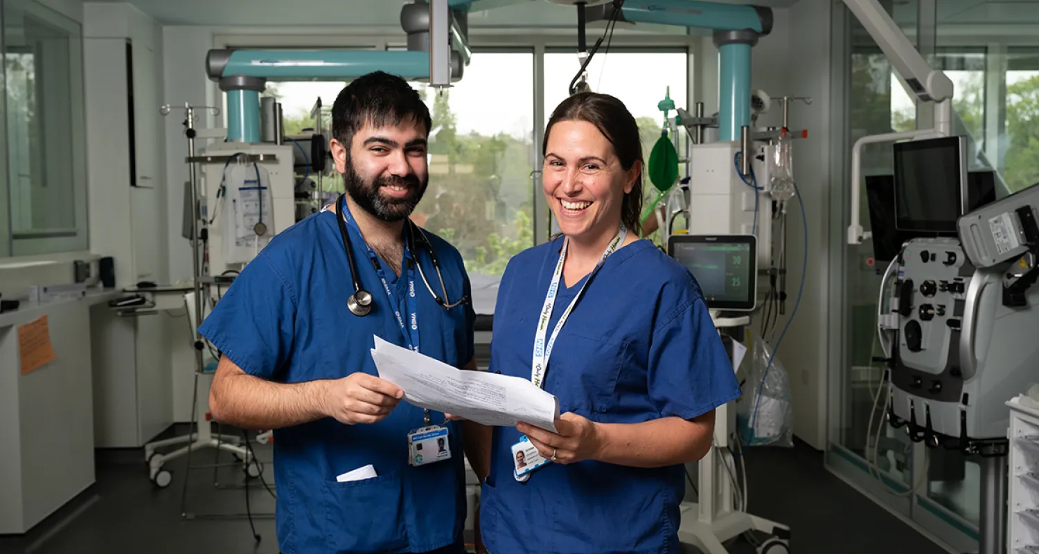 Picture of two doctors in blue scrubs standing at the camera and smiling