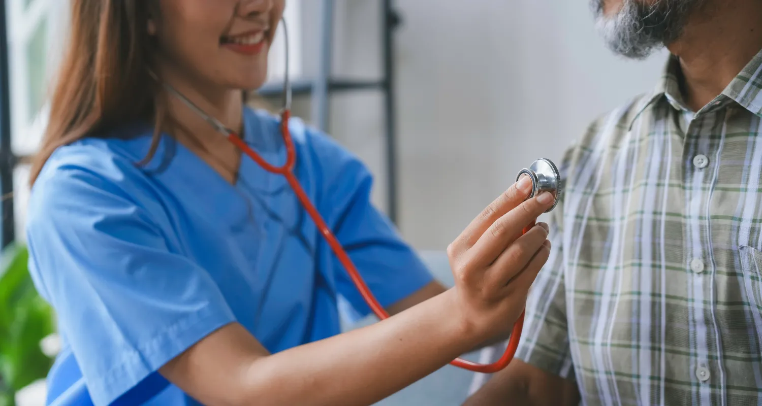 A doctor checking a patient's heartbeat in their home 