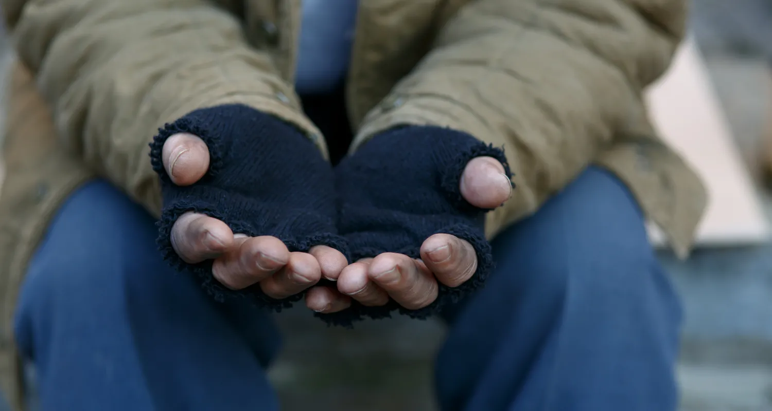 A homeless man wearing gloves