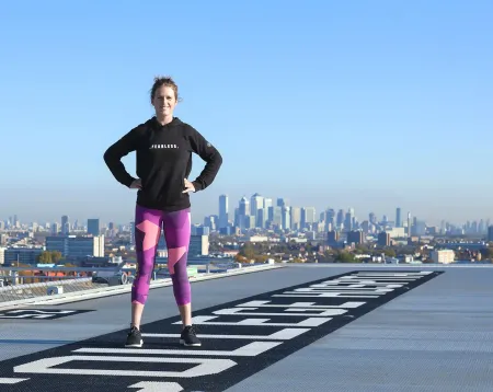 Picture of Kiko standing hand on hips on the King's helipad with blue skies and cityscape behind her
