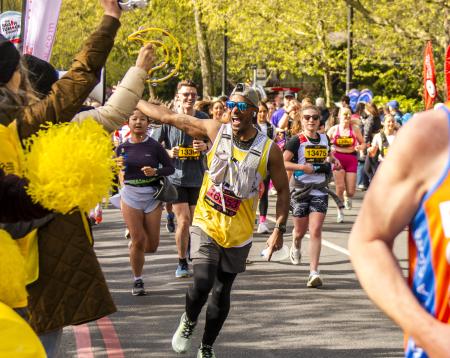 A runner in a yellow vest runs towards the camera