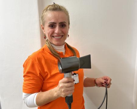 Woman in an orange King's volunteer t-shirt holding a hairdryer