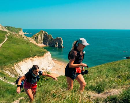 Two walkers walking in front of a beautiful Dorset coastline