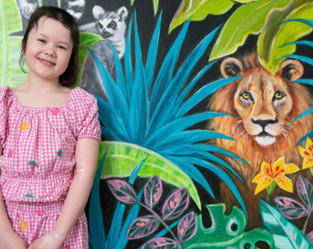 a child called Scarlet in front of a jungle mural