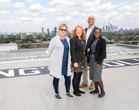 Picture of Gillian, Gail, Ian and Florence standing on the helipad with sky and cityscape behind them