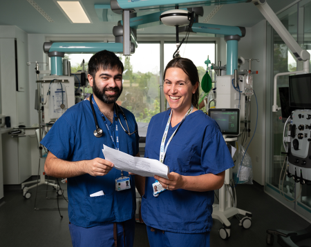 Picture of two doctors in blue scrubs standing at the camera and smiling