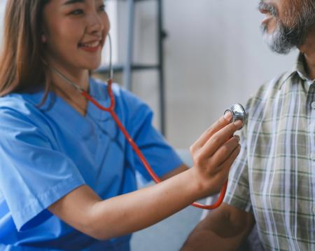 A doctor checking a patient's heart in their home