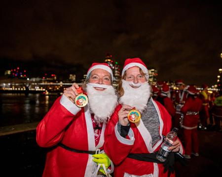 two ladies in santa suits with medals
