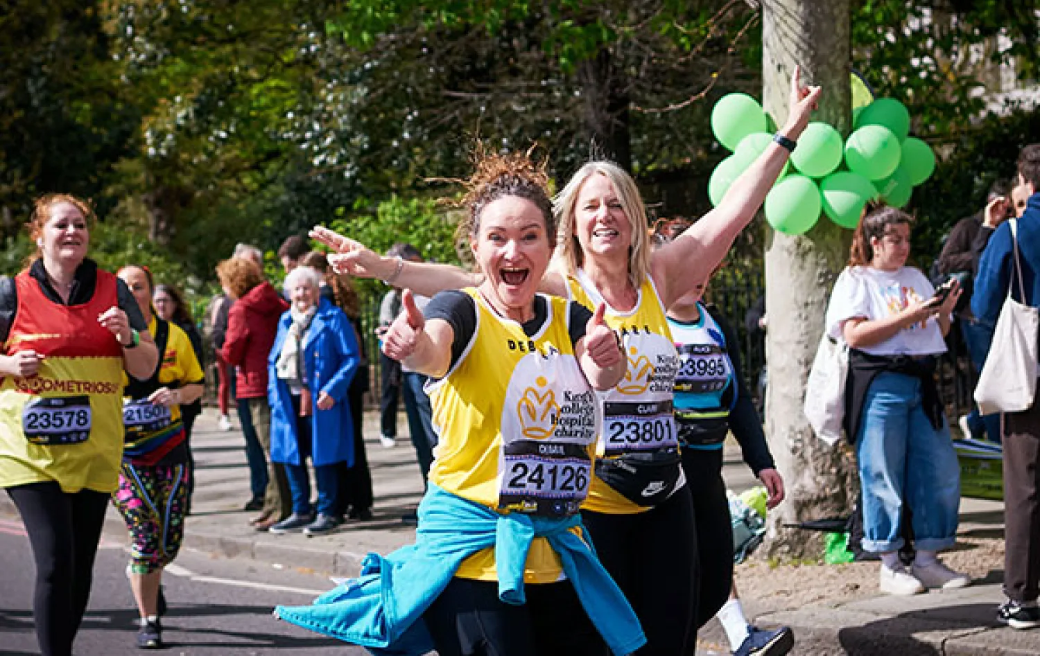 Two women in a King's College Hospital Charity running vest smiling at the camera and running in a race