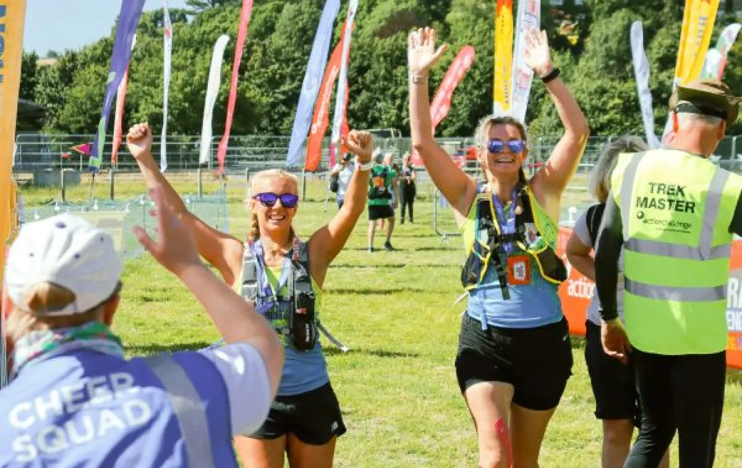 Two women walk towards camera with their hands in the air in celebration. 