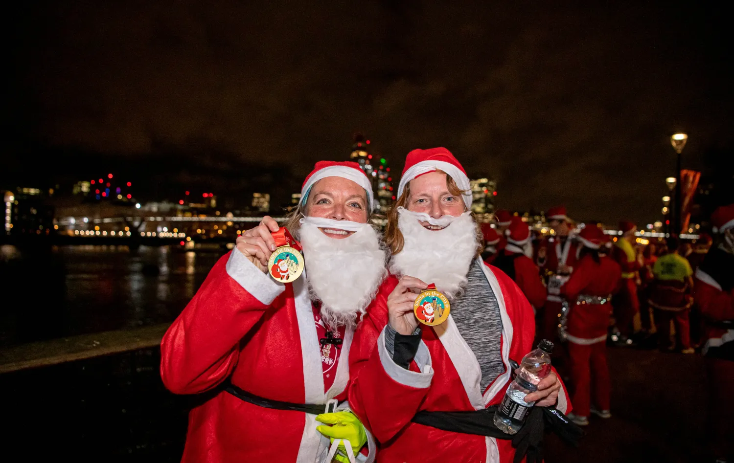two ladies in santa suits with medals
