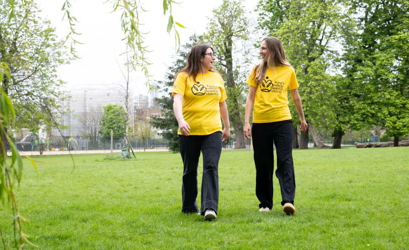 Two walkers in a park wearing yellow King's College Hospital Charity t-shirts