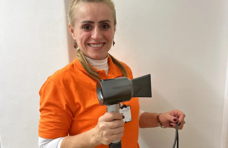 Woman in an orange King's volunteer t-shirt holding a hairdryer