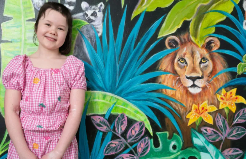 a child called Scarlet in front of a jungle mural