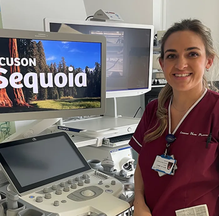 A female member of King's staff in purple scrubs standing in front of an ultrasound scanner, in a clinical setting.