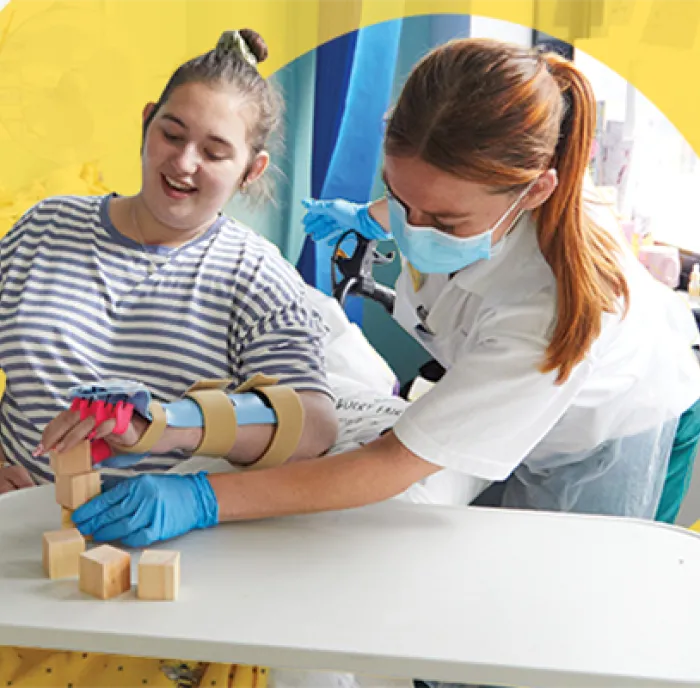 Picture of a nurse leaning over to play a game with a young woman patient