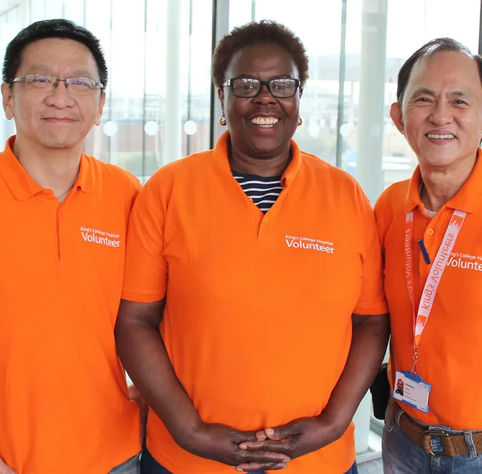 3 volunteers in orange t-shirts looking at the camera