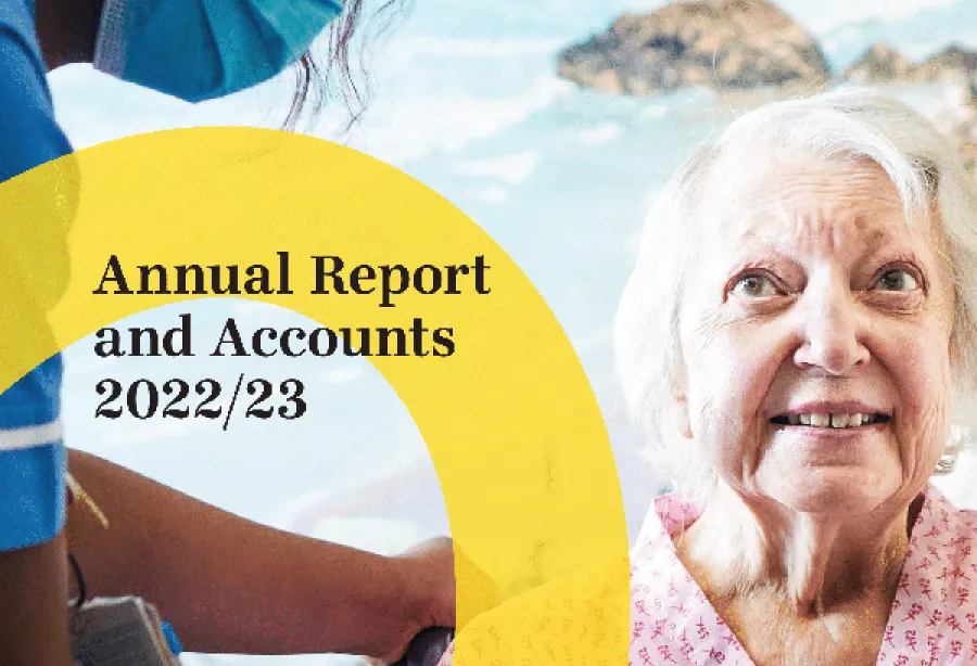 Picture of annual report front cover with nurse wearing mask while caring for elderly patient smiling with a picture of the sea in the background