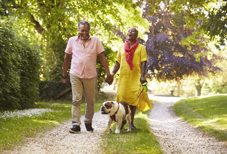 A man and a woman outside walking a dog