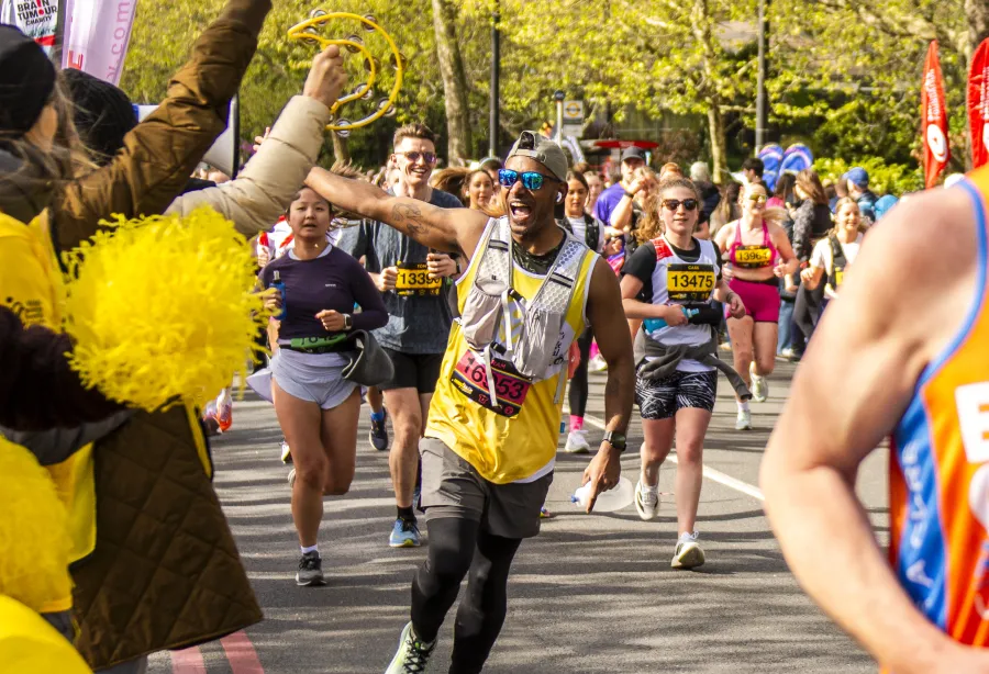 A runner in a yellow vest runs towards the camera