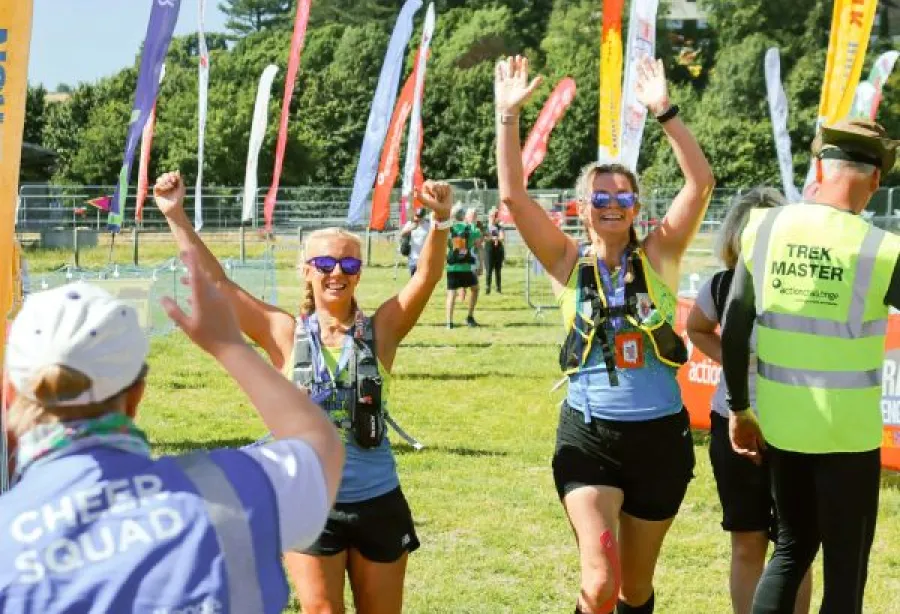 Two women walk towards camera with their hands in the air in celebration. 