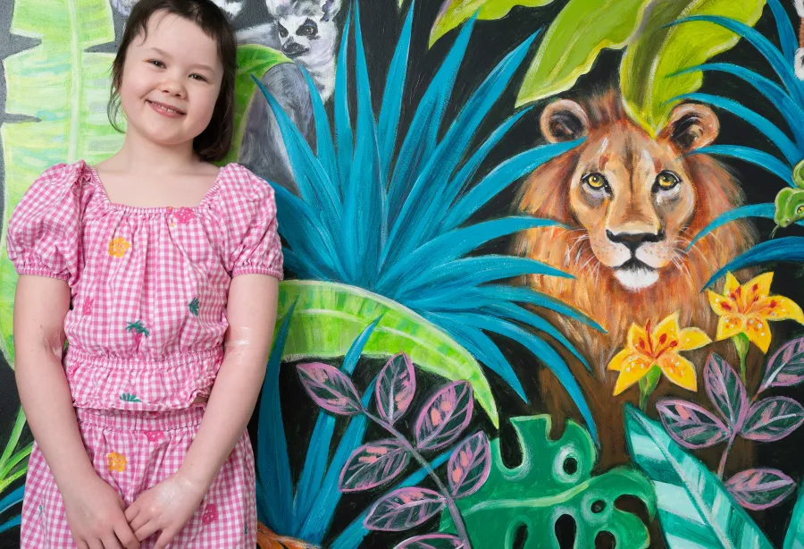 a child called Scarlet in front of a jungle mural