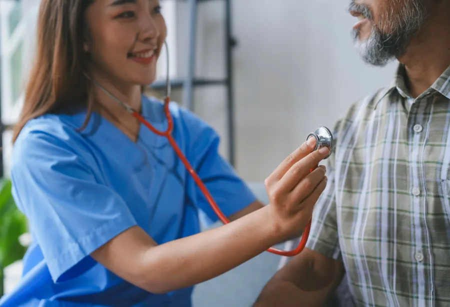 A doctor checking a patient's heart in their home